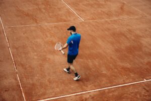 Athlete holding tennis racket on a clay court, summer sports action