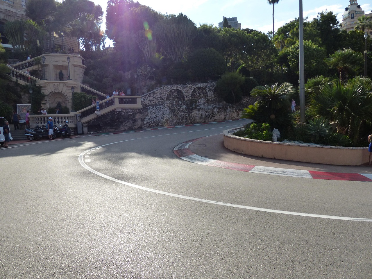 A tight bend on a street circuit lined with red and white kerbs and trees